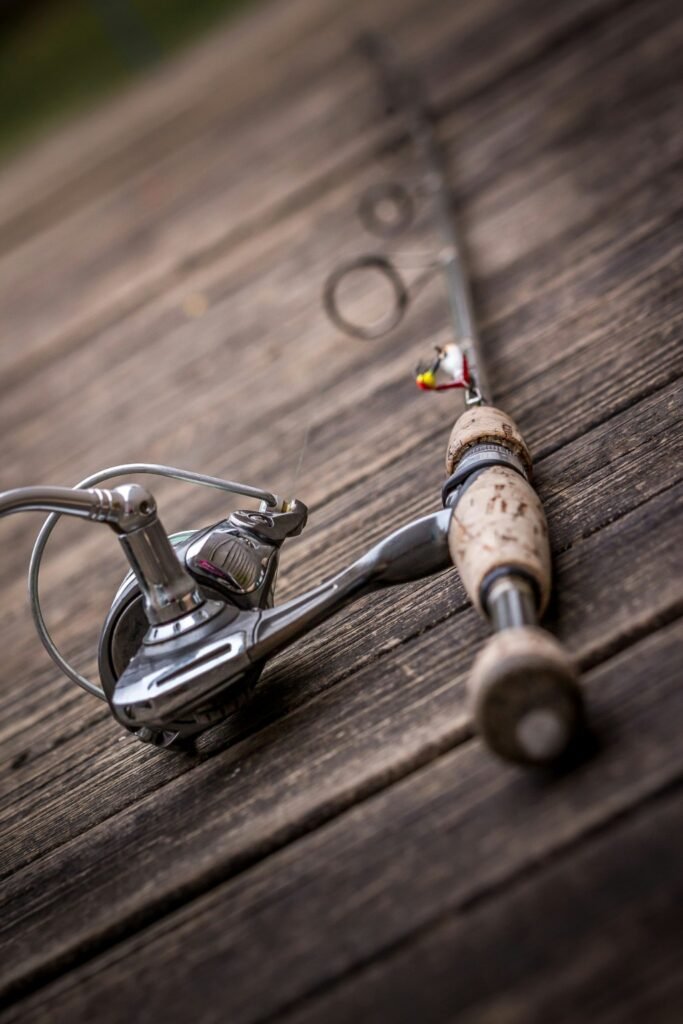 What You Actually Need to Start Fishing (And What You Don’t) Spinning fishing rod and reel resting on a weathered wooden dock with a small jig tied on
