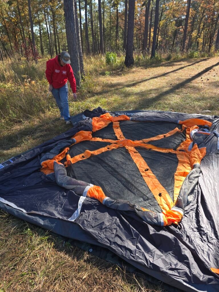 How to Set Up a Camping Tent (Step-by-Step for Beginners) Boy helping lay out a camping tent footprint while setting up a tent at a wooded campsite