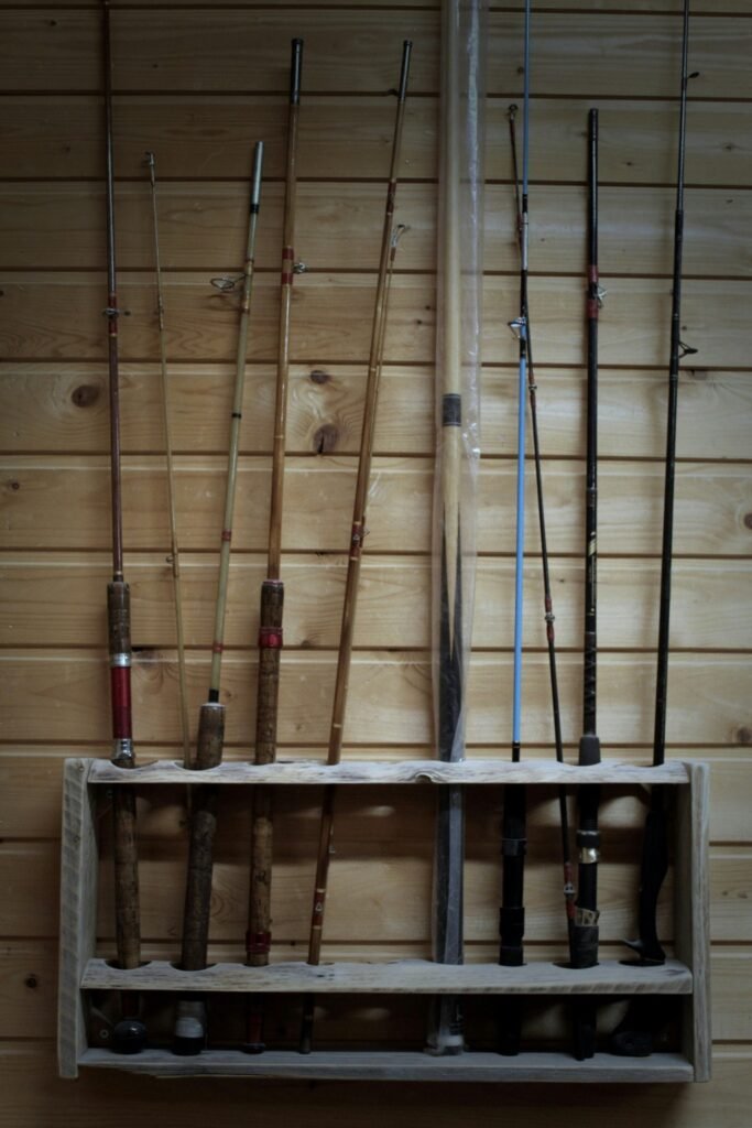Fishing rods of different lengths and styles displayed on a wooden wall rack