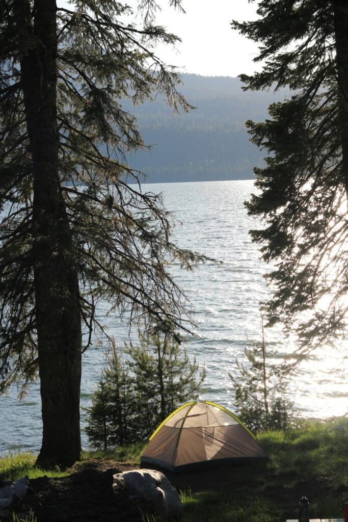 How to Choose the Perfect Campsite (What Actually Matters) Tent set up at a lakeside campsite surrounded by trees showing an ideal campsite location