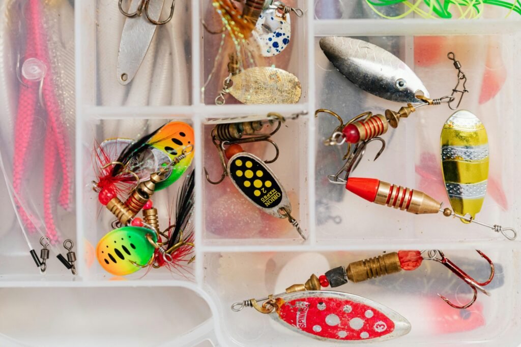 Understanding Fishing Baits and Lures (Types of Fishing Bait Explained for Beginners) Assorted fishing lures and spinners organized inside a tackle box